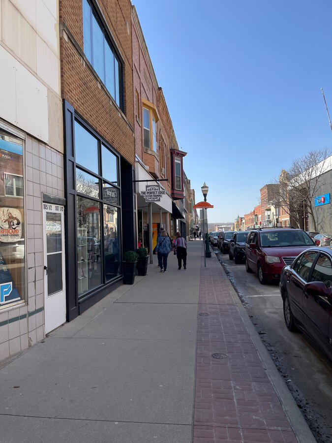 Brick storefronts and pedestrians along a quiet downtown street in Decorah.