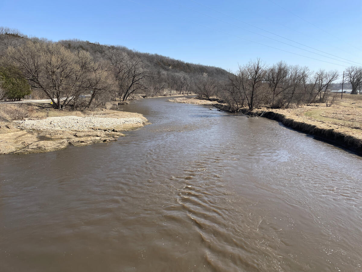 River flowing through a bare tree line and low hills on the edge of Decorah.