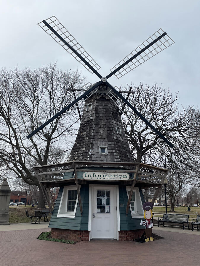 pella-information-windmill-visitor-center Windmill‑style visitor information center with teal siding and a small cutout figure at the entrance.