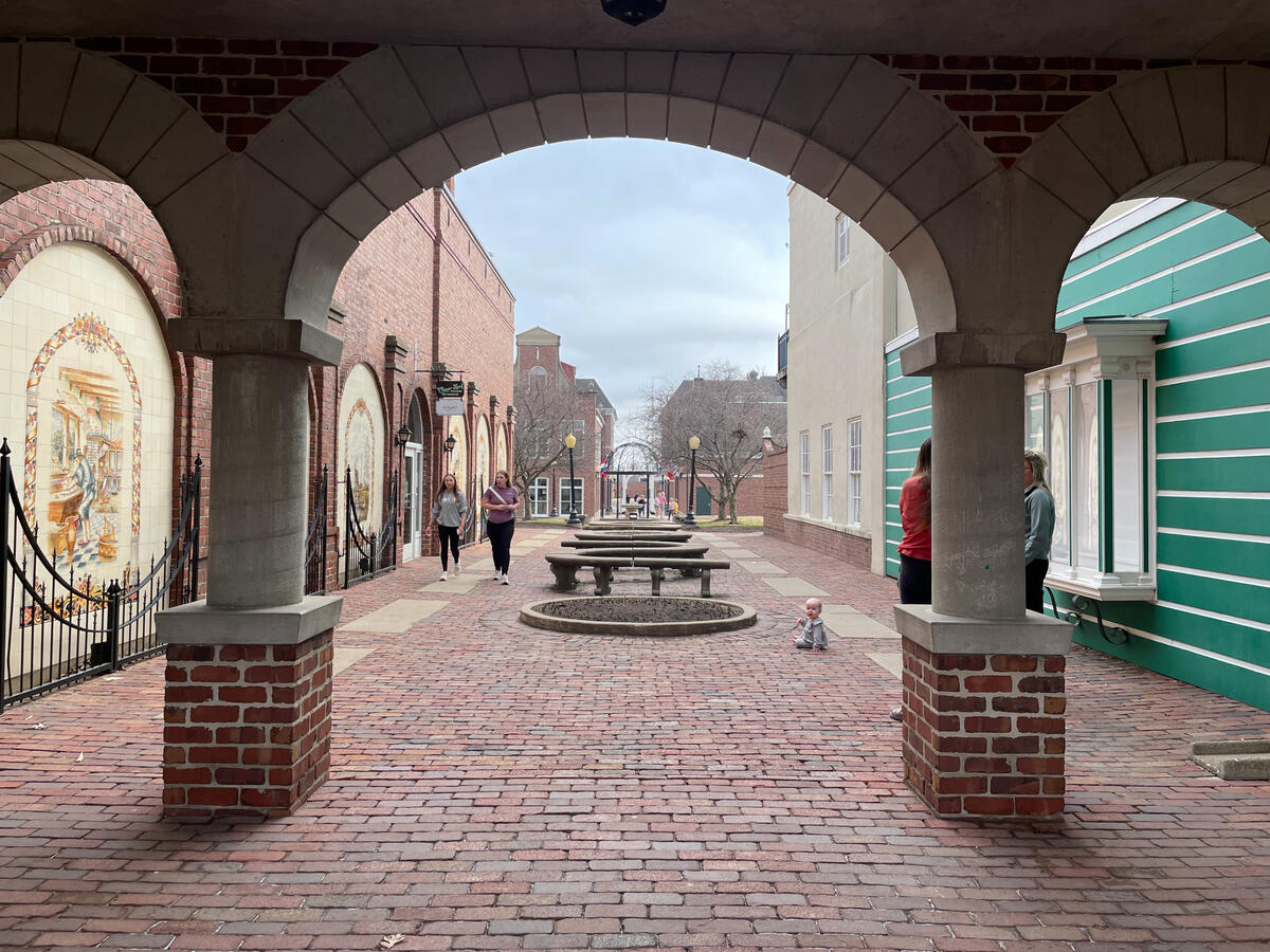 Brick walkway leading toward the Molengracht canal area lined with shops and public seating.