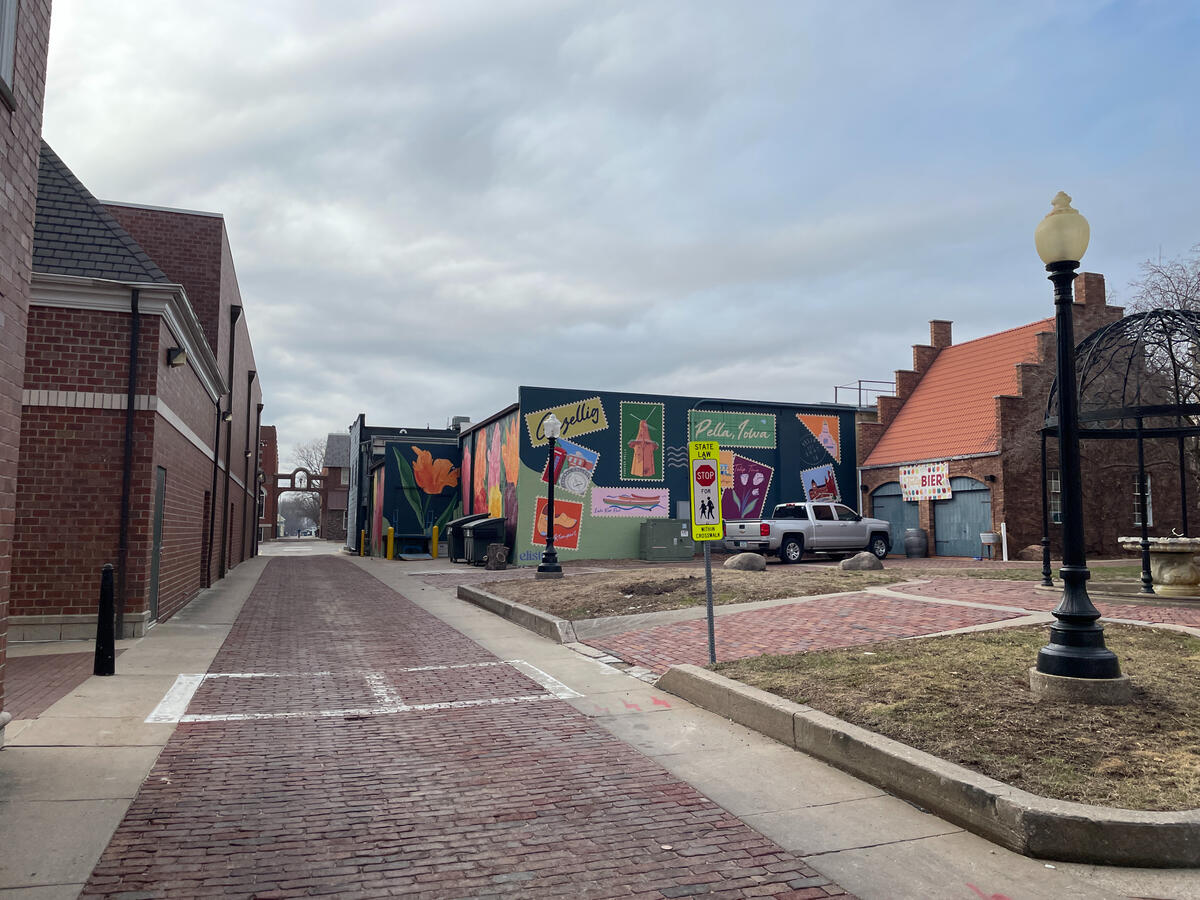 Street view in the Molengracht district with murals, brick buildings, and a pedestrian crossing sign.