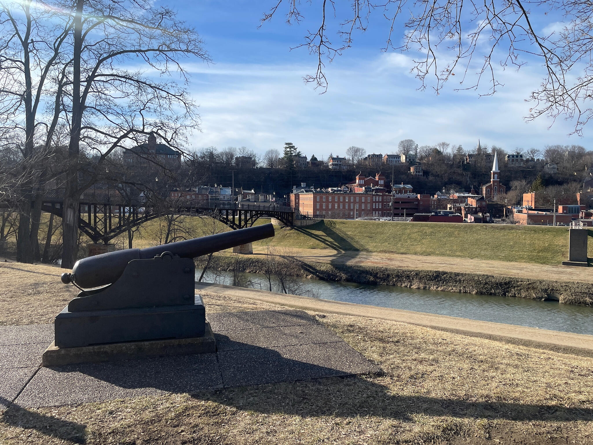 A historic black cannon in Grant Park overlooking the Galena River and the downtown skyline of Galena, Illinois.