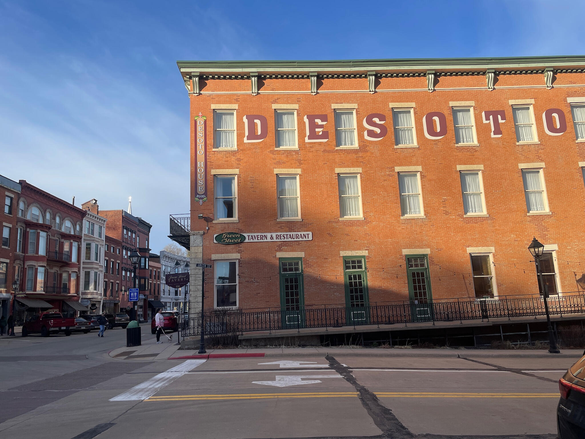Exterior of the historic red brick DeSoto House Hotel in downtown Galena, Illinois, with a line of boutique storefronts visible across Main Street.