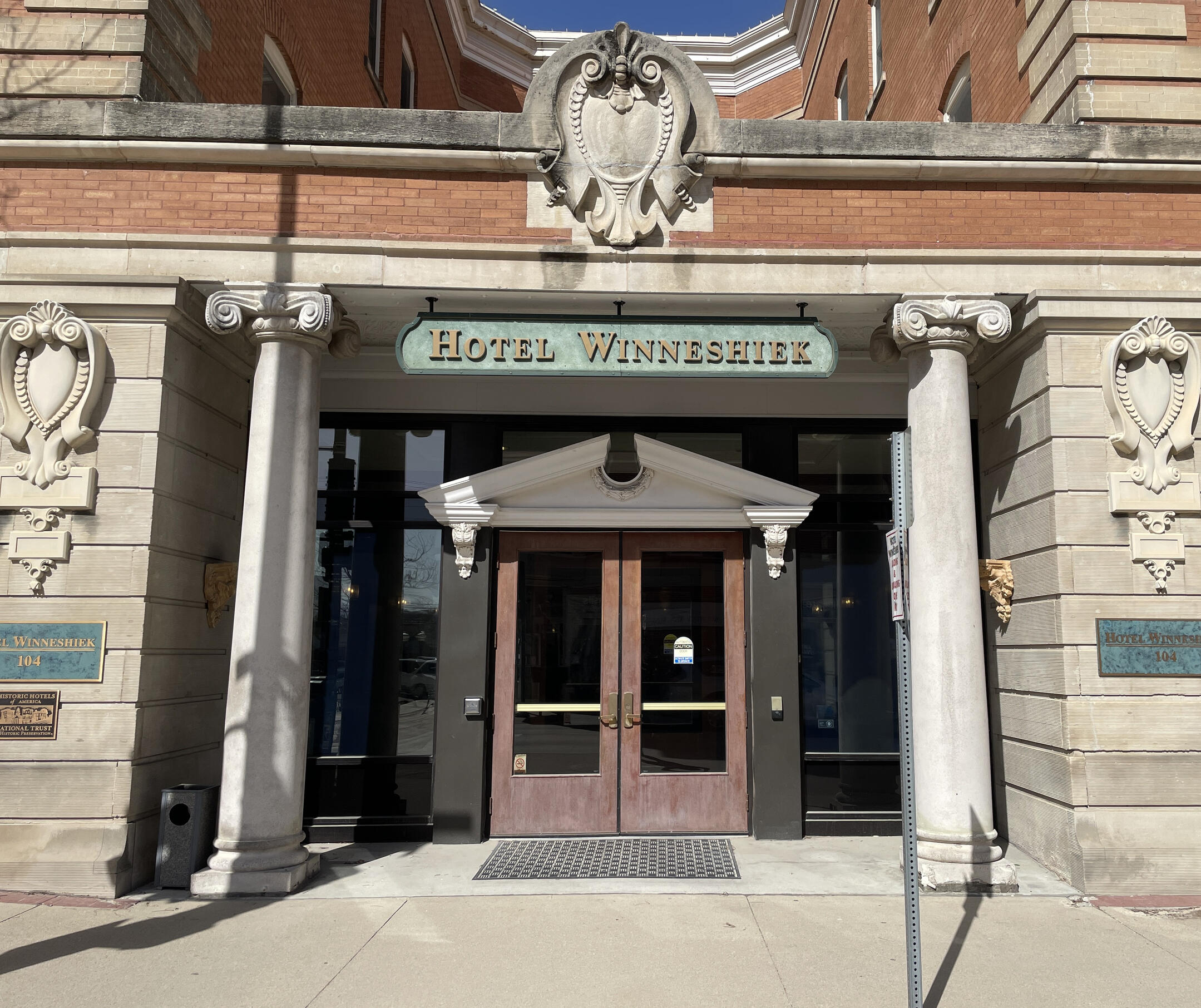 Stone entrance of Hotel Winneshiek with carved columns and historic plaques marking its National Register listing.