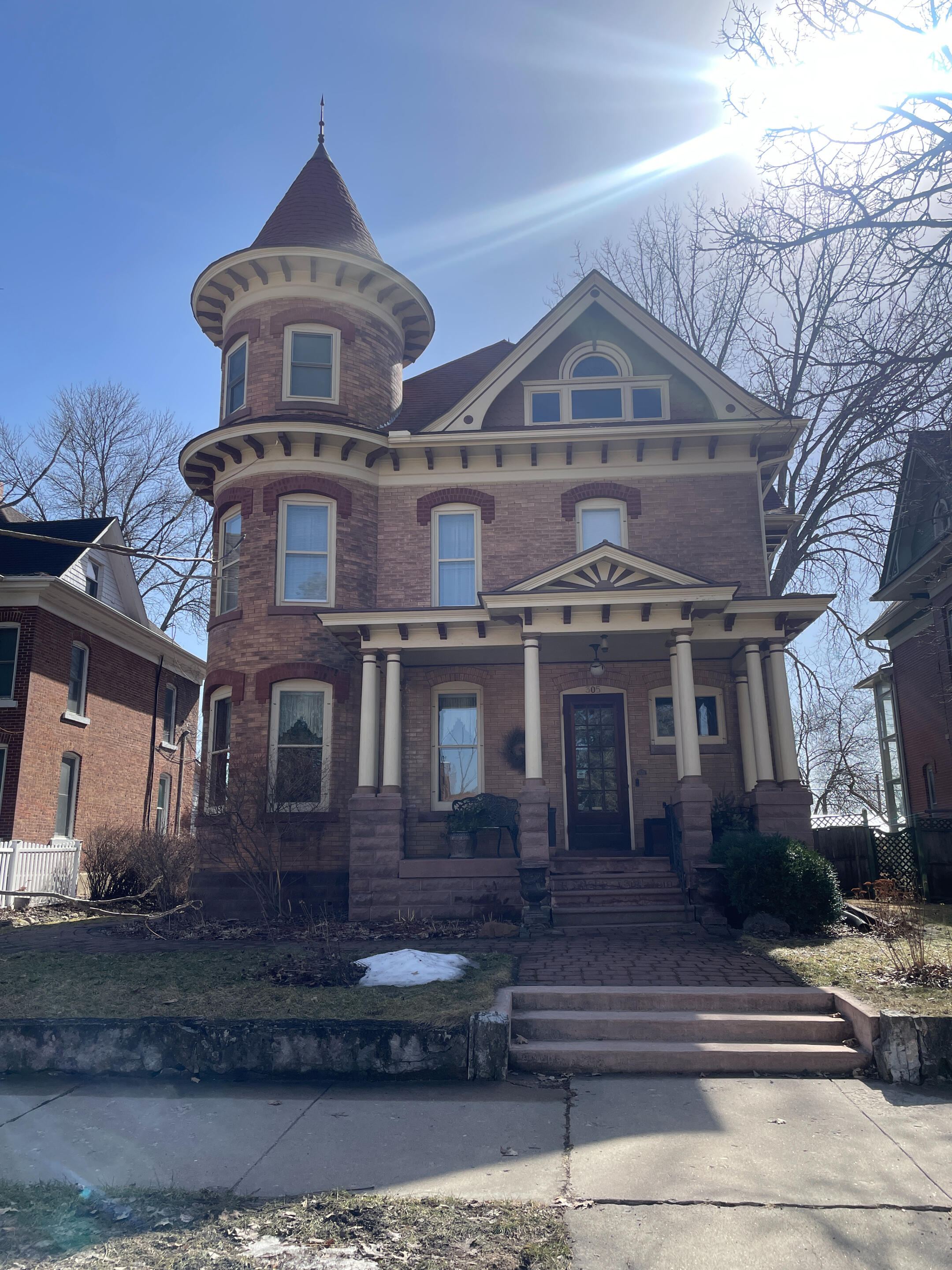 bb-on-broadway-victorian-exterior-decorah Historic Victorian house with a round turret, tall windows, and a columned porch at B&B on Broadway in Decorah.