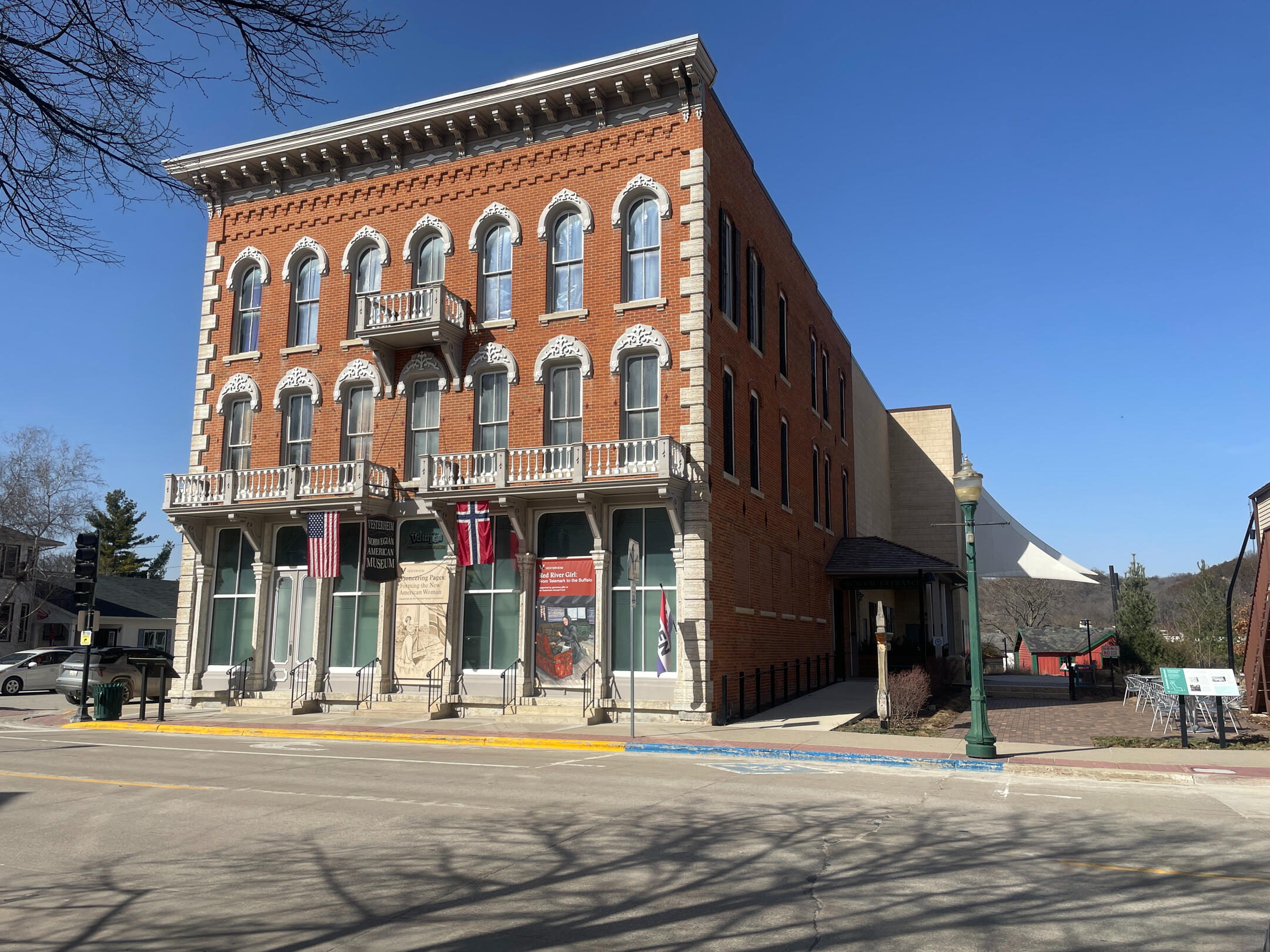 Three‑story brick Vesterheim Museum building with arched windows, flags, and carved stone details in Decorah.